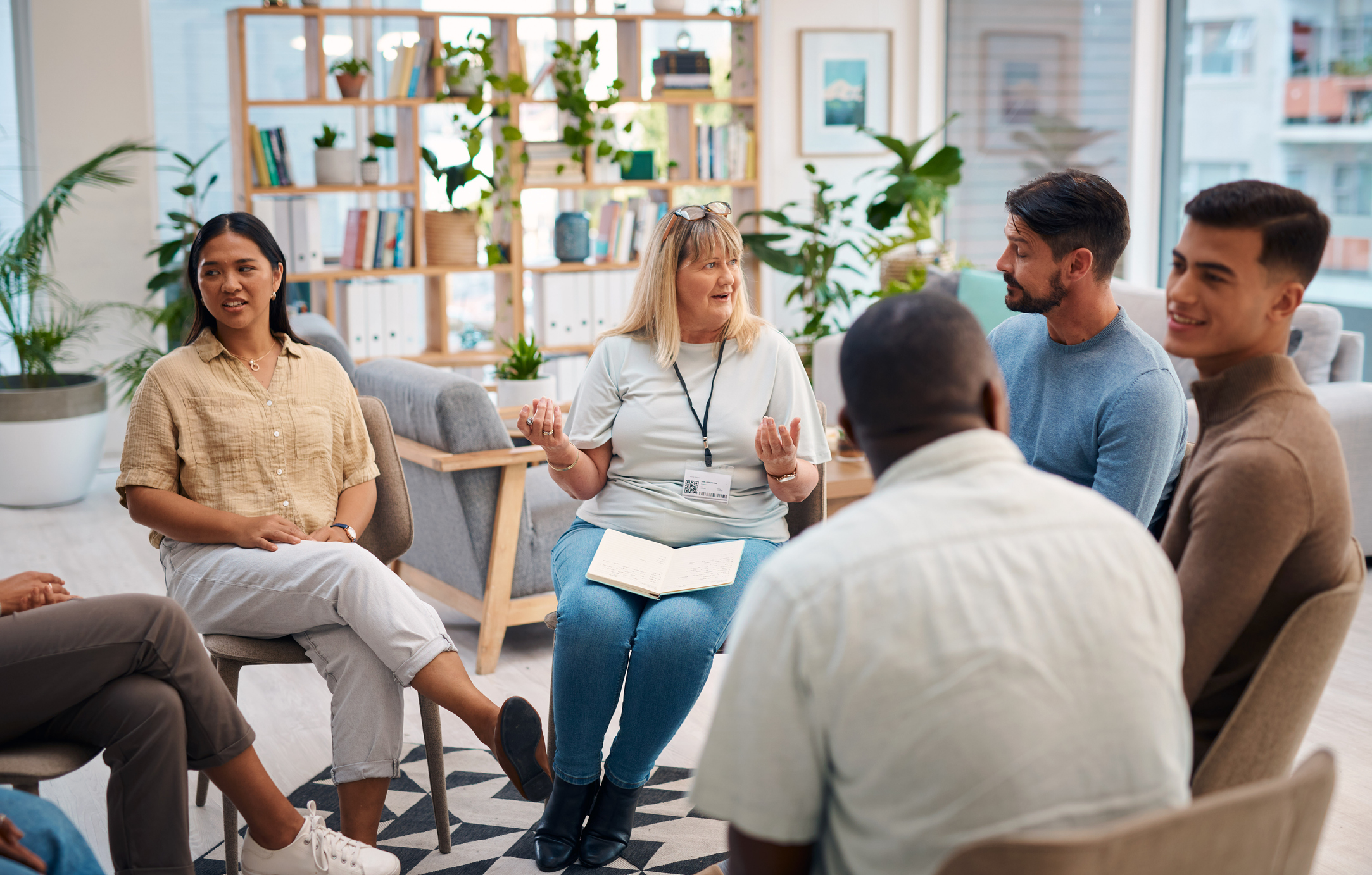 A small group in a warm, plant-filled office having an open discussion